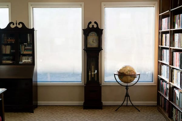 A corner of the library featuring a vintage clock, globe, and bookshelves.