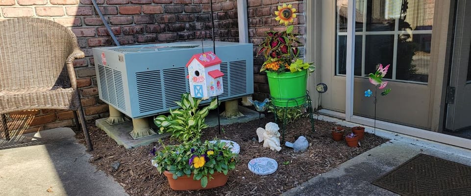 Colorful patio garden with flowers and decorations outside a door.