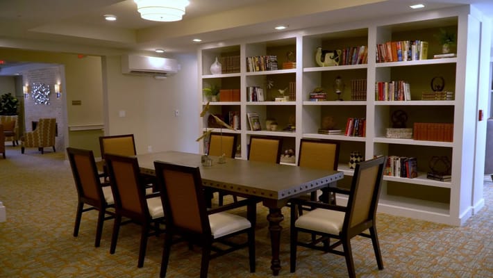 A cozy common area with bookshelves and a large table