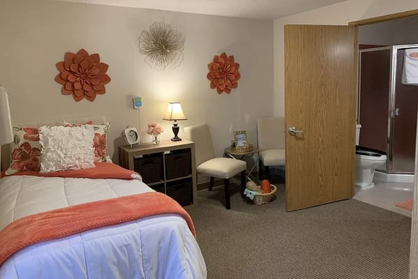A comfortable bedroom featuring a bed, chair, and decorative wall art.