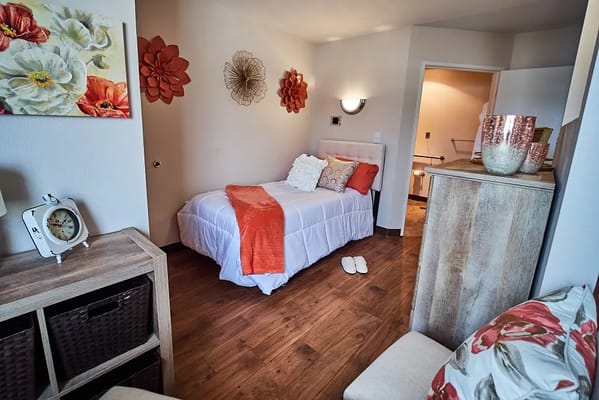 A cozy bedroom with a bed, decorative pillows, and wall art.