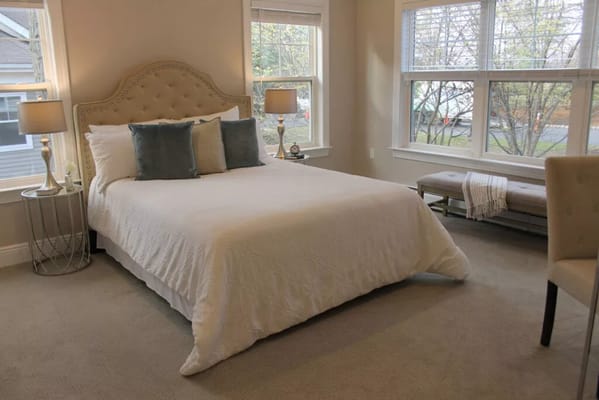 Well-decorated bedroom with a bed, decorative pillows, and natural light.