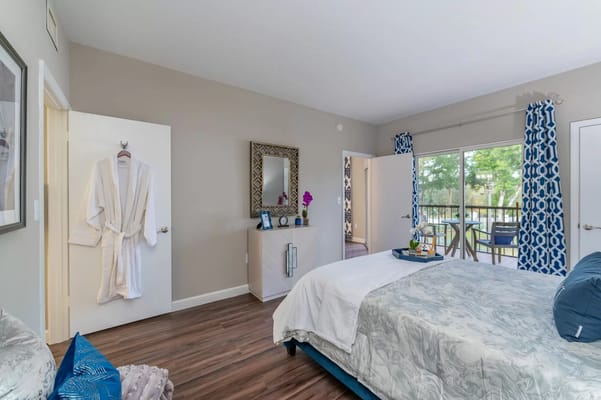 A well-decorated bedroom featuring a bed, mirror, and balcony access.