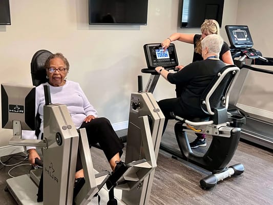 Residents using exercise equipment in an activity room