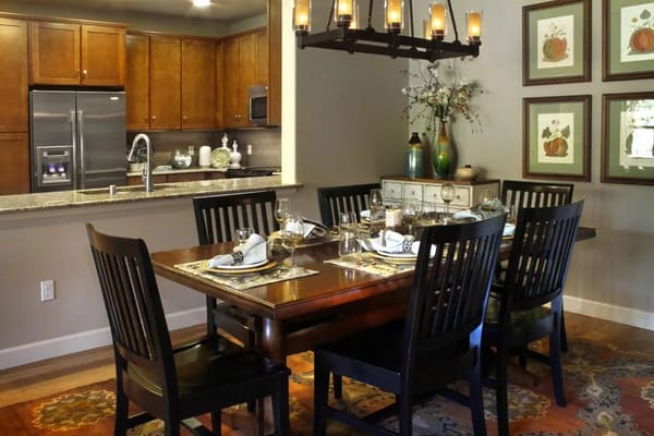 Dining table set with plates and glasses in a warm-toned kitchen and dining area