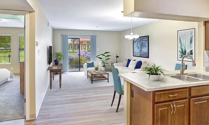 Cozy living room and kitchen area with large windows and modern decor.