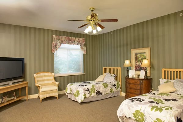 A cozy bedroom with two beds, a window, and a TV in Garden Terrace.