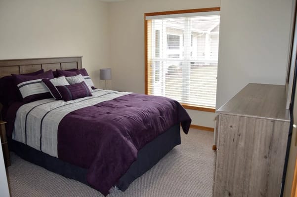Bedroom with a purple bedding set and large window