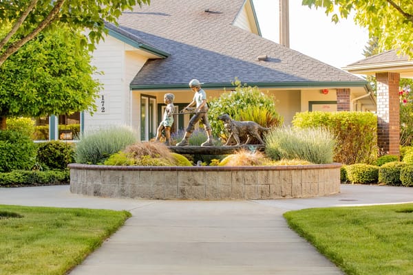Statue of children and a dog in a garden area