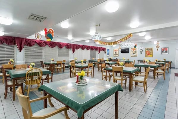 Spacious dining area with green tablecloths and floral centerpieces