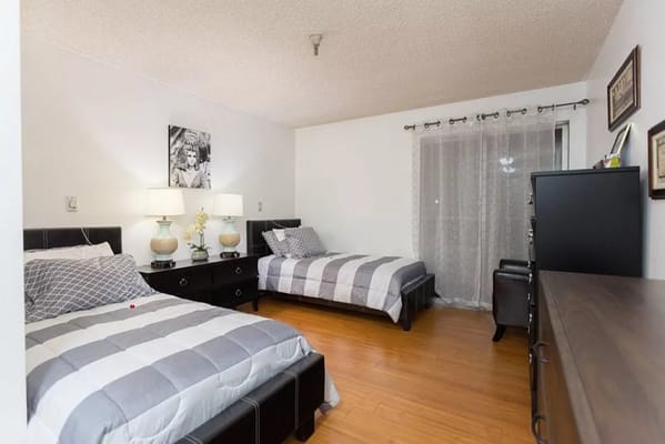 A cozy shared bedroom with two beds, nightstands, and a dresser.