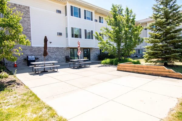 Outdoor patio space with tables and grill at Glenwood Senior Apartments