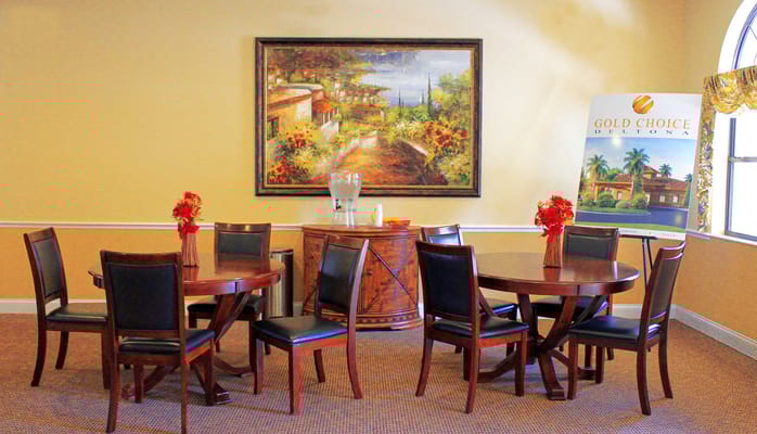 Dining area with tables and chairs, featuring decorative flowers and artwork