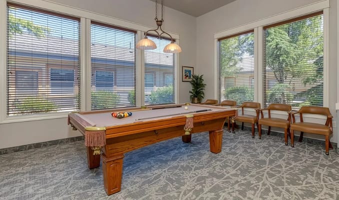 Pool table in a bright common area with large windows
