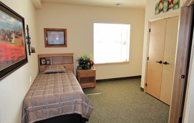 Cozy private room with a bed and a window at Gracewood Advanced Assisted Living.