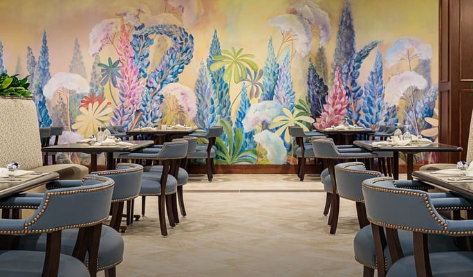 Elegant dining room with floral mural and tables set for dining