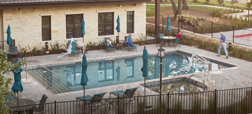 Outdoor pool area with residents relaxing on the patio