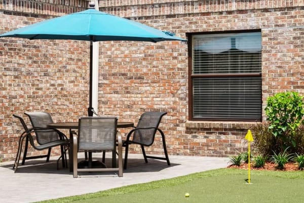 Outdoor seating area with patio umbrella and golf putting green