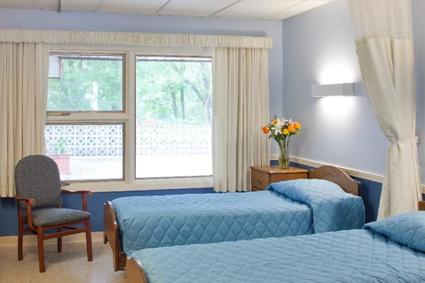 Bright resident room with two beds and flowers