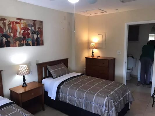 Cozy bedroom with two beds, bedside tables, and a painting.