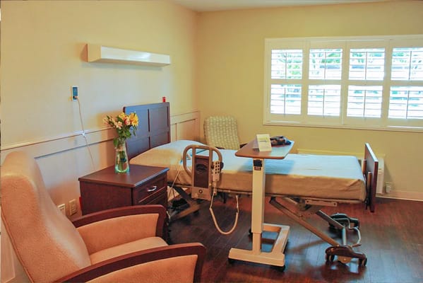 A well-furnished resident room with a hospital bed