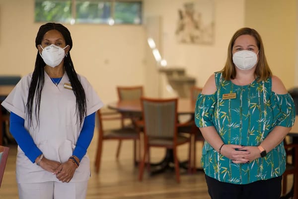 Two staff members in a common area, both wearing masks