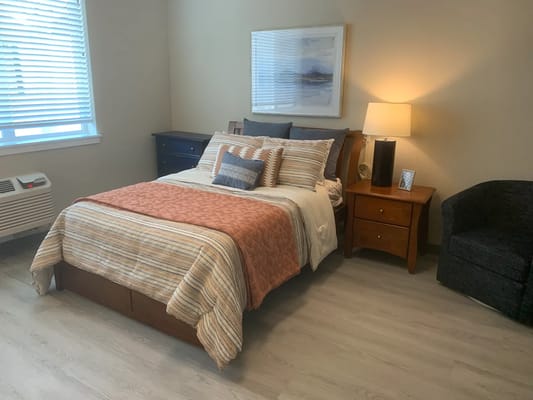 A well-furnished bedroom with a bed, nightstand, and armchair.