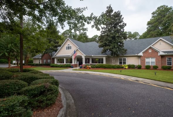 Front view of Harbor Cove Memory Care with American flag and landscaped garden