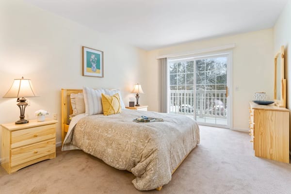 Well-lit bedroom featuring a bed, nightstands, and a balcony