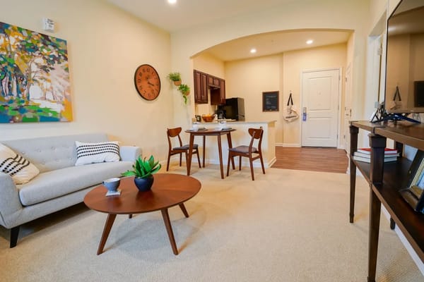 A cozy living room featuring a gray sofa, a wooden coffee table, and a small dining area.