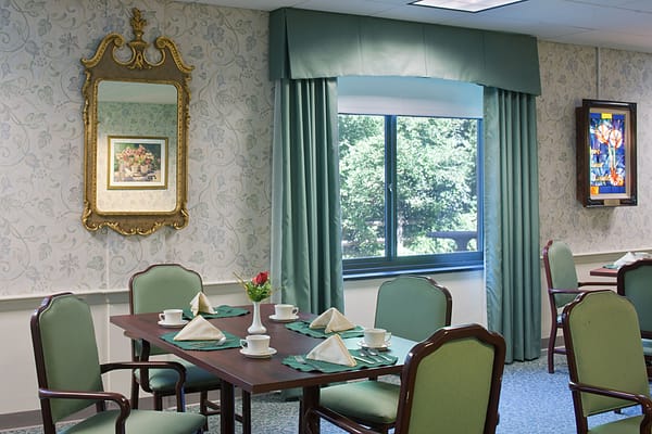 A dining room with green decor, table settings, and a large window