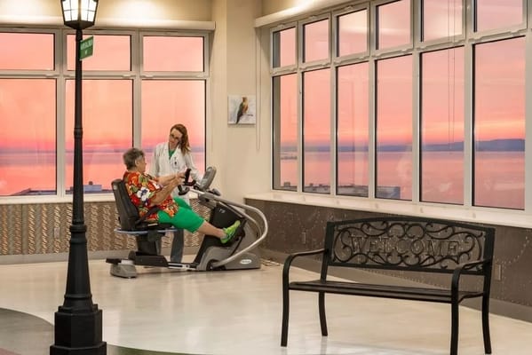 A resident exercising with staff assistance in a bright indoor space