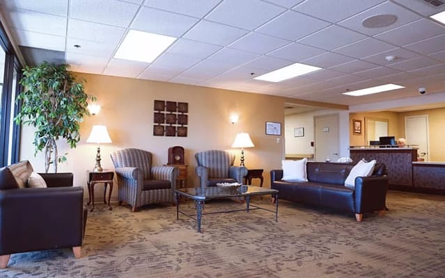 Cozy lobby with seating and lamps at Heatheridge Assisted Living