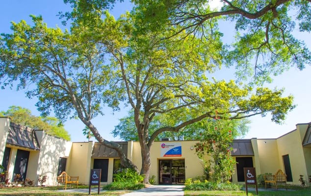 Exterior view of Heritage Park Care & Rehabilitation Center with large trees.