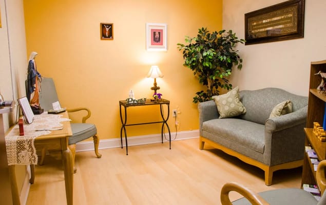 A cozy lounge area with a couch, side table, and religious decorations.