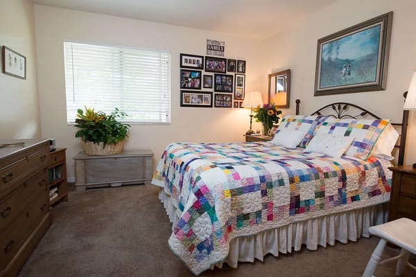 Well-decorated bedroom featuring a colorful quilt and family photos.