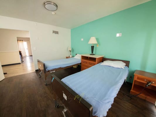A shared bedroom with two hospital beds and teal walls
