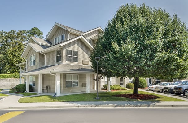 Exterior of Holiday Columbia Pines senior living facility with trees and parking lot