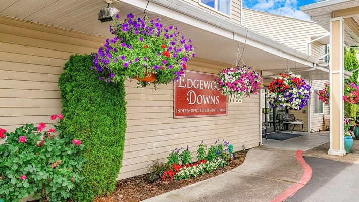 Entrance of Edgewood Downs with colorful flower baskets and signage.