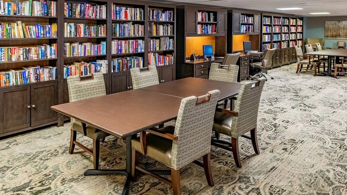 Library with bookshelves and tables in senior living facility