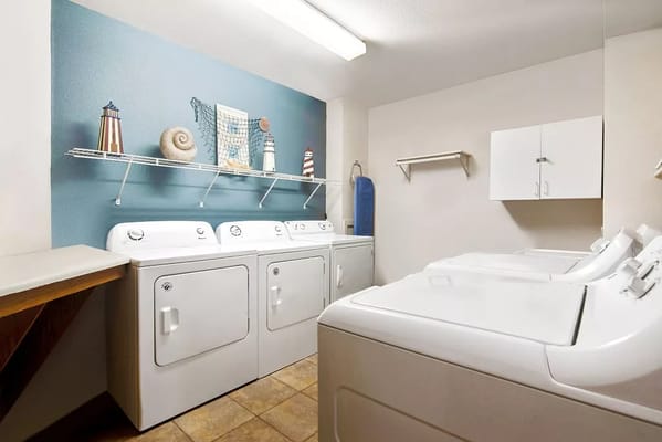 Bright laundry room with several washing machines and decorative items on the wall.