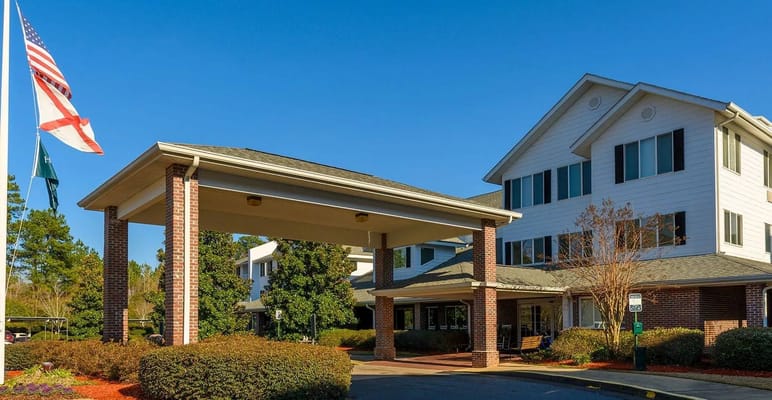 Entrance of Holiday Monarch Estates with flags and shrubs