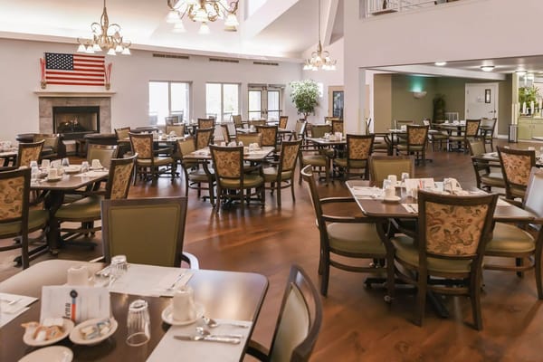 Brightly lit dining room with tables and chairs set for dining