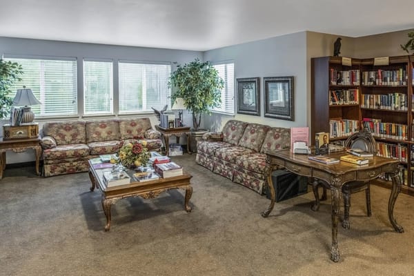 A welcoming living room with floral sofas, a coffee table, and book shelves.
