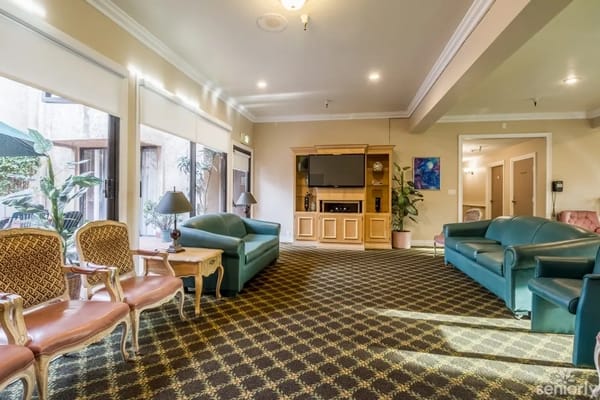 Spacious lounge with green couches and elegant chairs