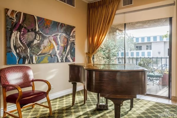Piano and chair in a sunlit corner with artwork on the wall