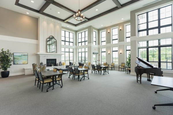 Bright and spacious common area with tables and a piano