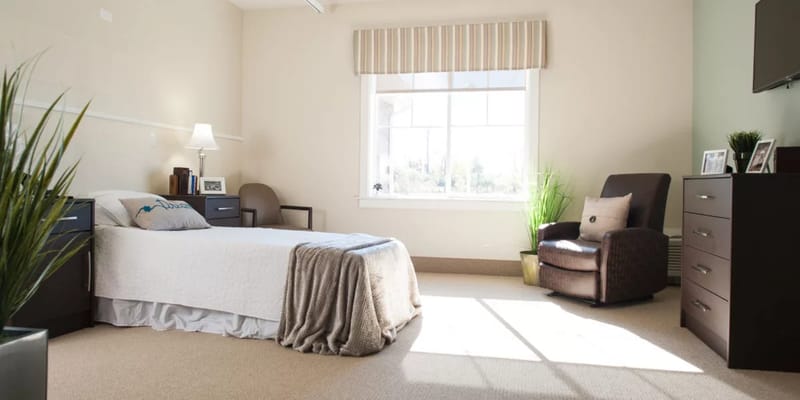 A cozy bedroom featuring a bed, chair, and ample natural light.