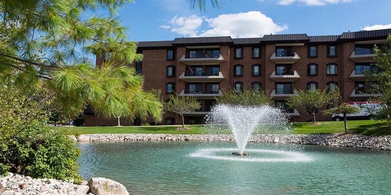 Outdoor view of a pond with a fountain and building