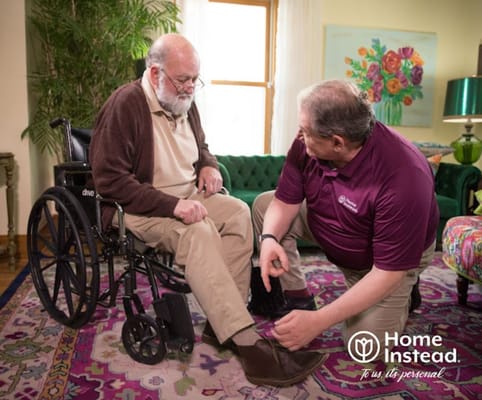 Caregiver assisting a senior man in a living room